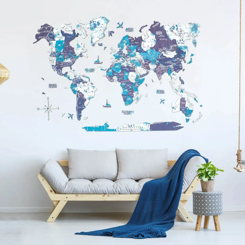 A large world map wall decal in shades of blue, purple, and white is displayed on a white wall above a light wood bench with gray cushions and a navy blue throw blanket.